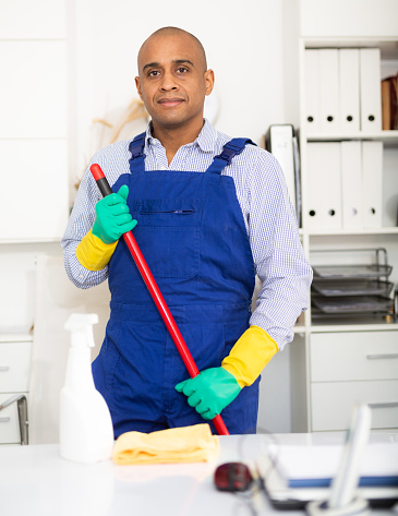 Male cleaner in protective uniform at company office