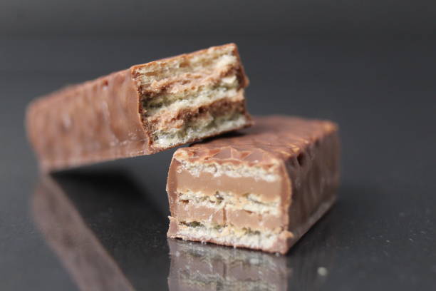 istock chocolate candy from waffle sheets and chocolate filling praline ganache. Bar cake in chocolate glaze on a black background. Chocolate Sweets Day 1449458476