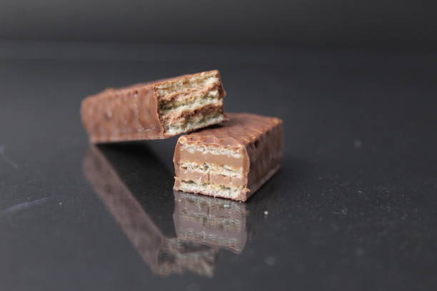 istock chocolate candy from waffle sheets and chocolate filling praline ganache. Bar cake in chocolate glaze on a black background. Chocolate Sweets Day 1449458486