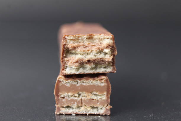 chocolate candy from waffle sheets and chocolate filling praline ganache. Bar cake in chocolate glaze on a black background. Chocolate Sweets Day