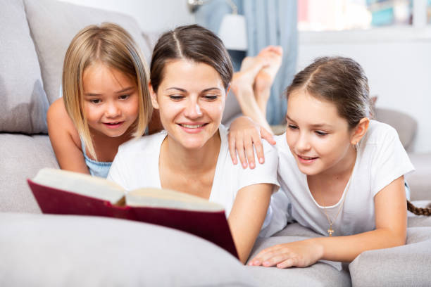 istock Woman reading book to daughters on sofa 1449459174