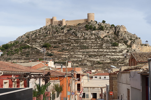 Castalla, Alicante, Spain, December 15. 2022: Towers and fortified walls of the Castalla castle seen from the town, Alicante. Spain