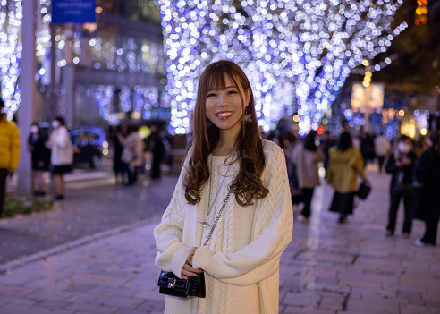 Portrait of young woman under Christmas lights