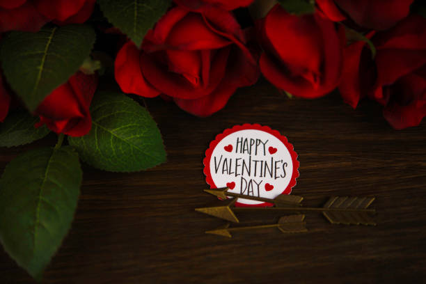 Valentine's Day background with red roses and a note reading HAPPY VALENTINE’S DAY on a dark wood table