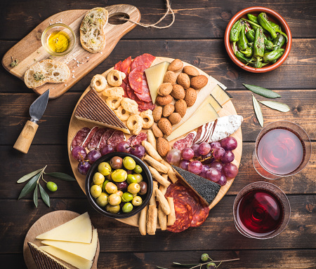 Appetizers boards with assorted  delicatessen cheese, salami, grape and nuts. Charcuterie and cheese platter, Spanish style and ingredients: olives, Pimientos, Chorizo, picos, cheese Semicurado. Top view, wooden rustic table