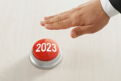 businessman pressing 2023 button on wood background.