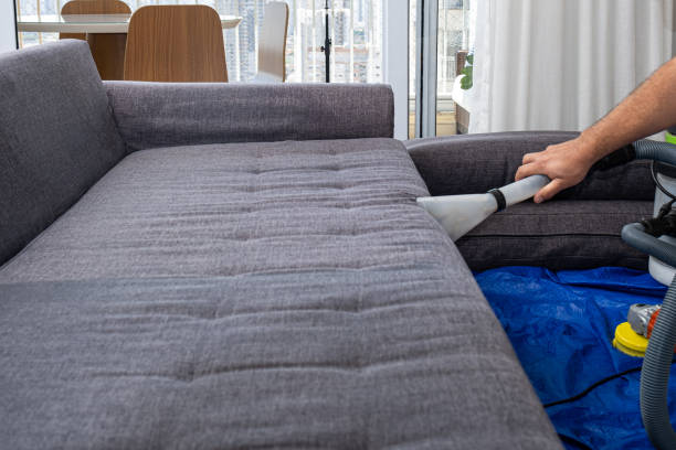 istock Man using a special vacuum to clean sofa cushions_side view. 1449472288