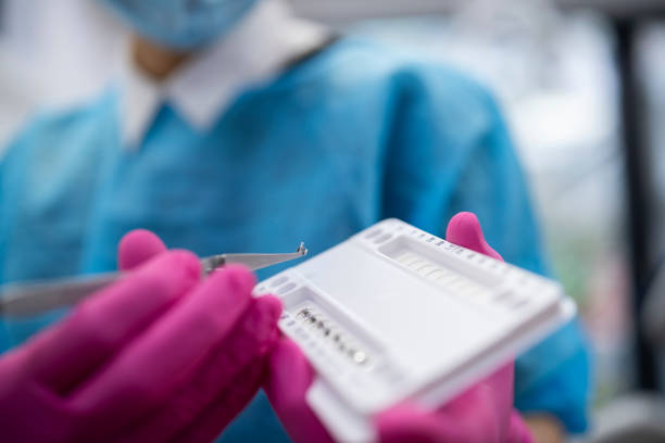 istock Othodontist putting metal braces with tweezers. 1449475981