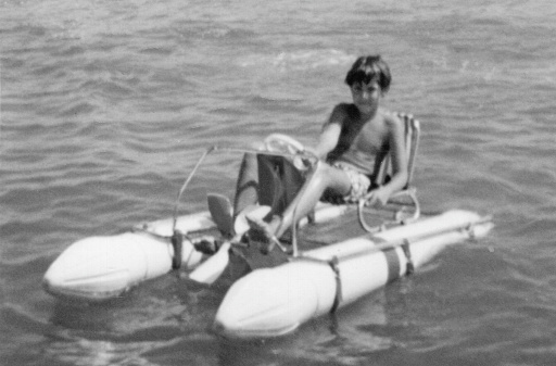 Image taken in the 60s: Smiling boy sitting in a pedal boat