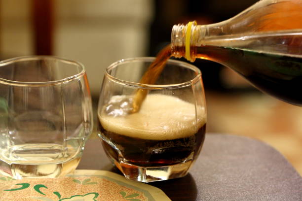 Pouring cold drink (Cola) into glass from plastic bottle.
