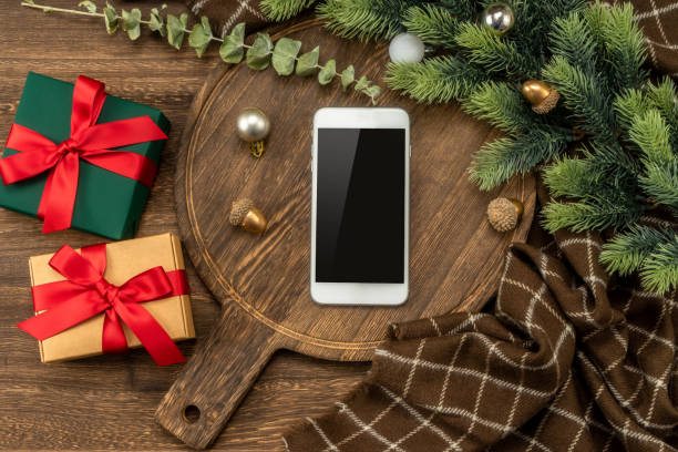istock Smart phone on wooden cutting board with Christmas decorations. 1449495488