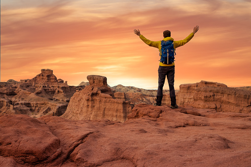 Hiker open arms at mountain peak reaching life goal, freedom, success and happiness, achievement in mountains at sunset in Cafayate, Salta, Argentina - Adventure travel concept