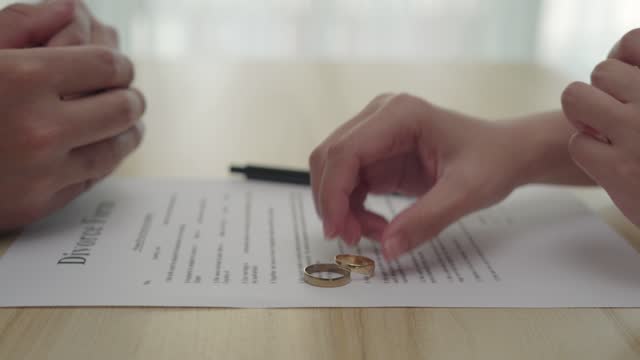 Family conflicts and love problems concept. The hands of the husband and wife with the divorce paper. The wedding ring was removed on a contract.