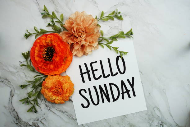 istock Hello Sunday text with orange flower bouquet on marble background 1449503437