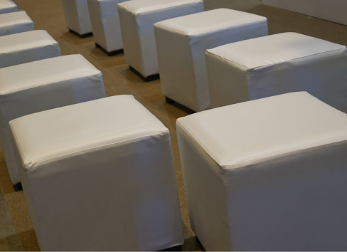Cube shaped leather upholstered chairs line up in room, Interior background