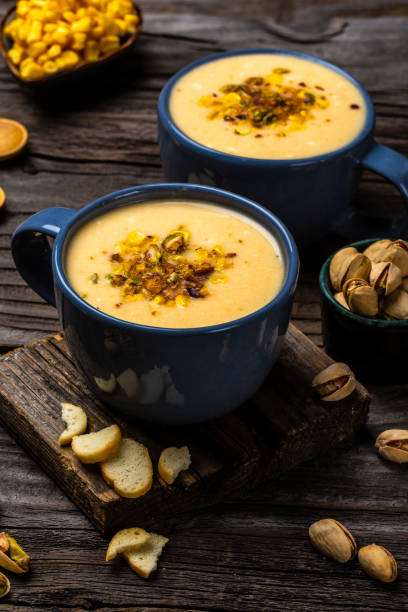 istock Corn Soup, Vegan cuisine. Traditional autumn corn soup. Served with corn cobs, roasted pistachios and croutons, Restaurant menu, dieting, cookbook recipe, top view 1449520111