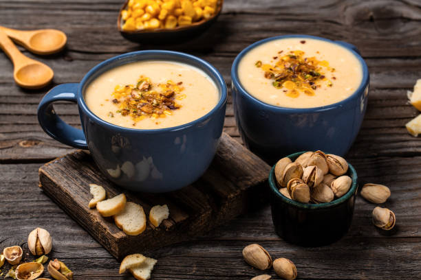 istock Corn Soup, Vegan cuisine. Traditional autumn corn soup. Served with corn cobs, roasted pistachios and croutons, Restaurant menu, dieting, cookbook recipe, top view 1449520115