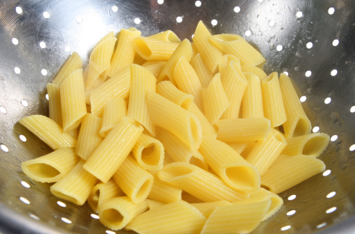 Close-up of penne pasta draining in colander