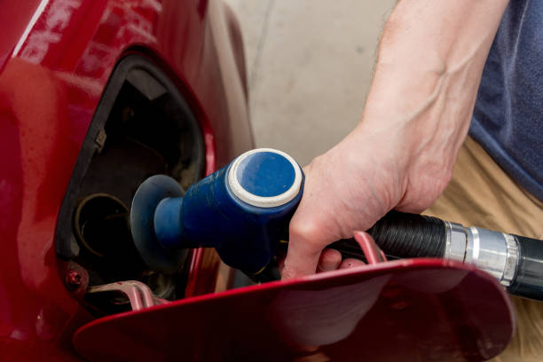 un uomo che tiene la pompa che riempie la benzina. pompando benzina nel serbatoio. un'auto fa rifornimento sulla stazione di servizio - pompa daria foto e immagini stock