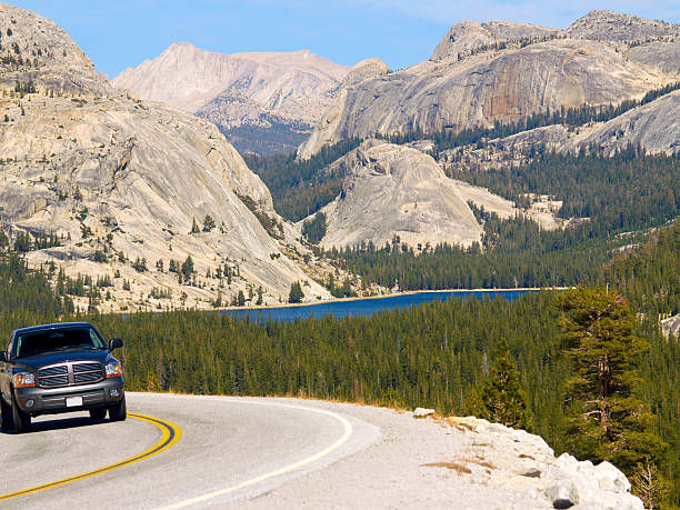 Yosemite vista Pickup truck rounding curve in front of High Sierras in Yosemite indigo truck stock pictures, royalty-free photos & images