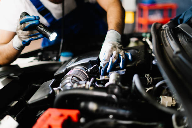 istock Close up mechanic working and checking engine in garage, Technician is wearing gloves and shine a flashlight on the car, Car Service and Automobile Maintenance Concept 1449529021