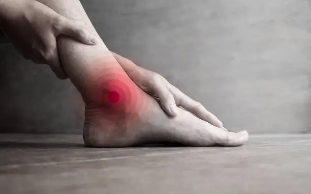 Inflammation of Asian young mans ankle joint and foot. Concept of joint pain, osteoarthritis or gout.