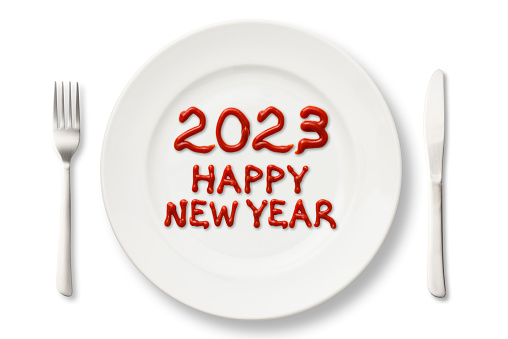 Close-up of 2023 HAPPY NEW YEAR written with ketchup on a white plate.