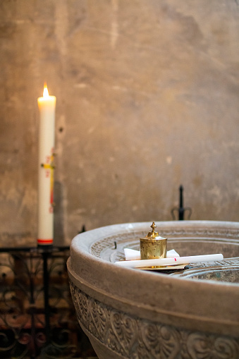 A vertical shot of candles and a small water pond for Christian baptism inside a church