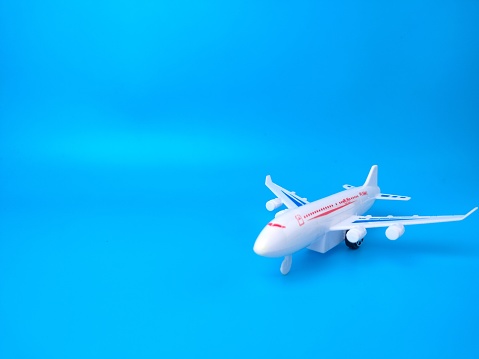 A white toy airplane isolated on an empty blue background