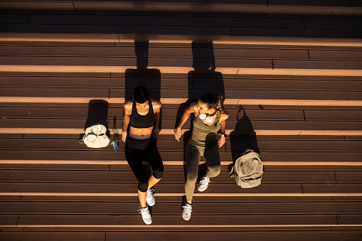 Best female friends sitting and resting on a sunny summer day after long run, aerial view from above