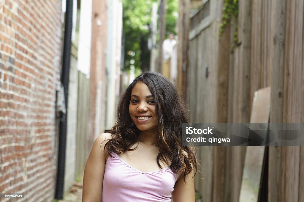 Smiling Mixed Race Hispanic Woman, Tank Top, Alley Hispanic woman standing in an alley.   - See lightbox for more 18-19 Years Stock Photo
