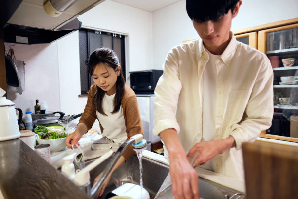 istock Couple washing dishes together in kitchen 1449542535
