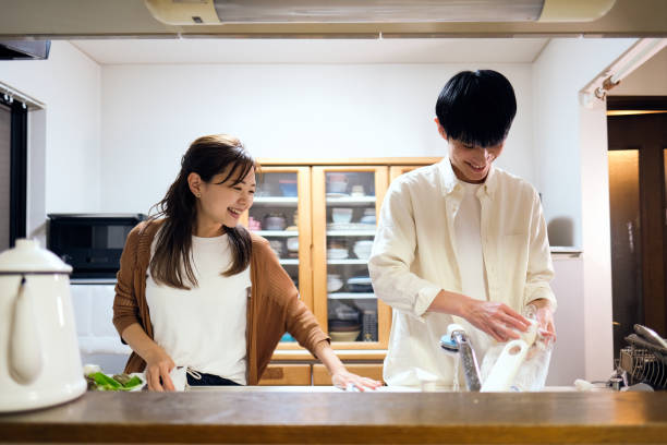 istock Couple washing dishes together in kitchen 1449542536