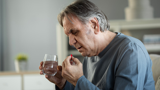 Old man taking medication at home