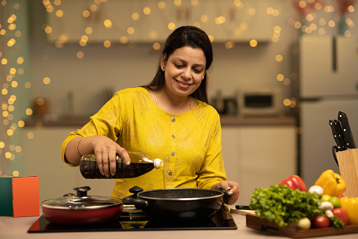 Portrait of Indian woman enjoying while cooking meal in the kitchen