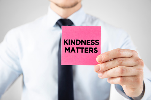 Businessman holding a pink business card with the message kindness matters