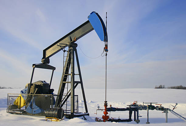 Pump Jack Against Blue Sky A oil and gas lease in a snow covered field. oil pump oil industry alberta equipment stock pictures, royalty-free photos & images