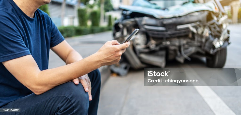 Man calling with phone to his insurance agent after traffic accident with a background of the crashed car, Car insurance an non-life insurance concept. Car Accident Stock Photo