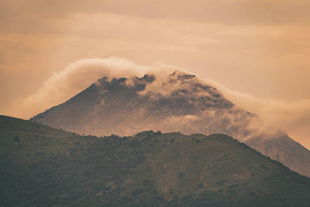 sunlight coming through the mountains and cloud clusters. Clouds over a volcanic mountain and mountains in front of it in volcanic island