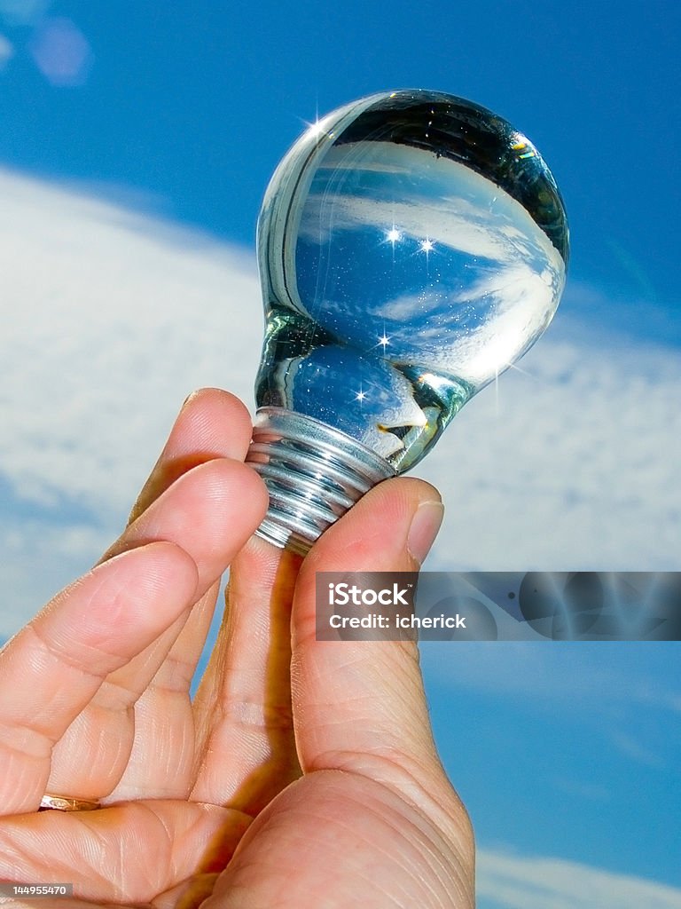 Eureka Man's fingers hold a lamp filled with water, on a background of the sky Cloud - Sky Stock Photo