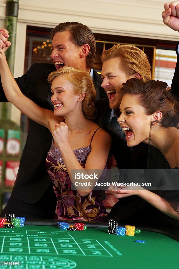Quatre amis en regardant la roue de spinning au casino - Photo de Adulte libre de droits