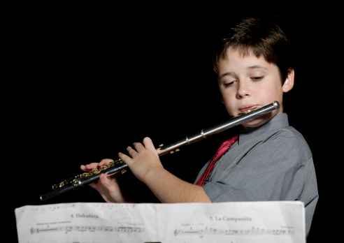 Young school boy practicing his flute pieces.