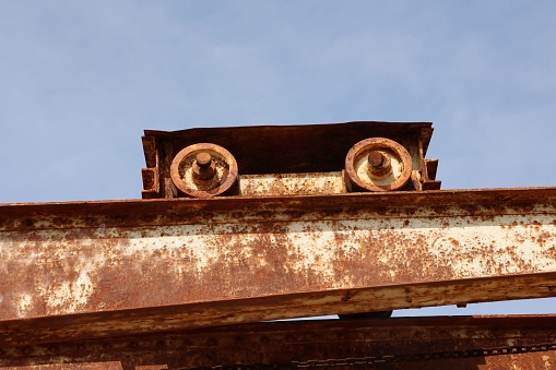 A closeup of a sunlit old rusty port crane with clear sky background