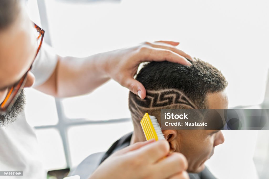Barber brushing designs on a clients hair Hairdresser working in barber shop Barber Shop Stock Photo