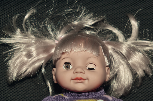 Strange female baby doll dressed in skirt and sweater open and close eyes