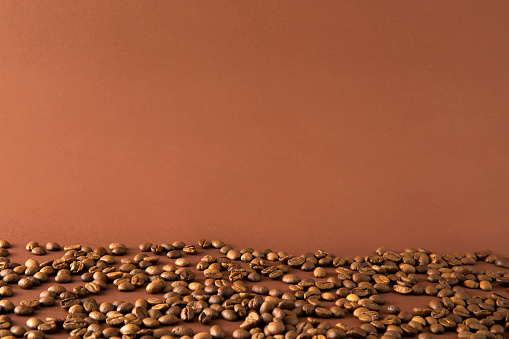 Heap of coffee beans on brown background