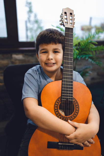 istock Young multiracial boy smiling while holding his acoustic guitar 1449566047