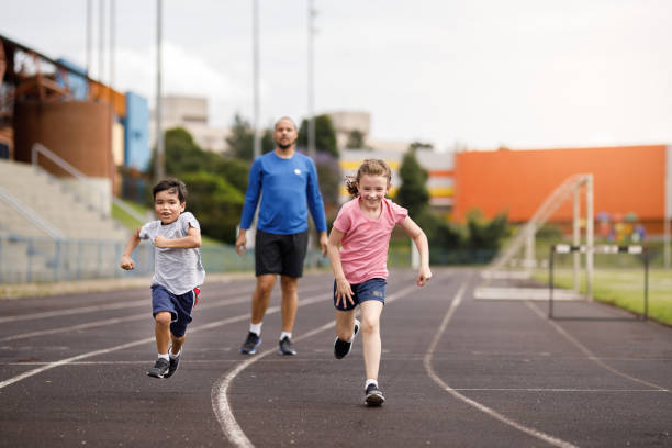 istock Kids having fun sprinting on the field with their dad 1449569891
