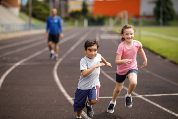 istock Siblings having fun running together while being watched by their father 1449569910