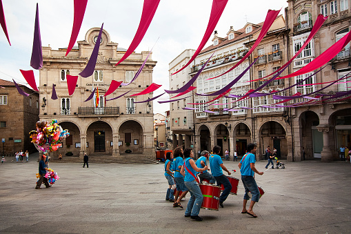 Ourense, Spain- June 21, 2011: Drummers in a street artists band, young musicians, in Mayor square, old town Ourense (Galicia, Spain) with  stone arches, Town hall in the background.